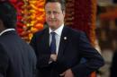 Britain's PM Cameron reaches into his pocket as he arrives for official photograph of Commonwealth heads of states during the CHOGM opening ceremony in Colombo