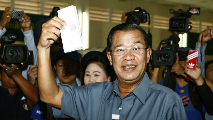 FILE - In this July 28, 2013 file photo, Cambodia's Prime Minister Hun Sen shows his ballot at a polling station in Takhmau town, south of Phnom Penh, Cambodia. The two rival parties claiming victory in Cambodia's general election reached an agreement Saturday, Aug. 3, 2013 with the state National Election Committee to investigate polling irregularities, a move that could smooth the way to ending the country's political deadlock. Hun Sen, in power for 28 years, has made clear that he believes the final results, due in mid-August, will favor him and that he will have another five-year term in office. With his overpowering influence over the state apparatus and the judiciary, he is almost certain to have his way. (AP Photo/Heng Sinith, File)
