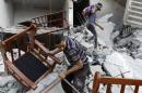 Men salvage belongings from the ruins of a home that residents say was hit by an Israeli air strike in Gaza City