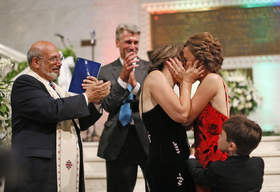Same-sex couple Margaret Miles and Cathy ten Broeke kiss after they were married just after midnight Thursday Aug. 1, 2013 on the steps of the Rotunda at Minneapolis City Hall by Mayor R. T. Rybak and Reverend James Gertmenian, left. Hundreds of family, guests and supporters of the more than 60 same-sex couples scheduled to be married at City Hall early Thursday gathered to celebrate the historic union. (AP Photo/Star Tribune, Brian Peterson)