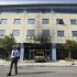 A security guard walks outside Microsoft's offices in northern Athens, Wednesday, June 27, 2012. Assailants attacked the offices of Microsoft early Wednesday, driving a van through the front doors and setting off an incendiary device that burned the building entrance, police said. (AP Photo/Thanassis Stavrakis)