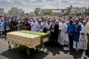 Thousands gather to pray at caskets of Imam Maulama Akonjee, draped in green top, and Thara Uddin in a municipal parking lot, Monday Aug. 15, 2016, in New York. Both were shot in the head as they left the Al-Furqan Jame Masjid mosque in the Ozone Park section of Queens as they left afternoon prayers Saturday. (AP Photo/Bebeto Matthews)