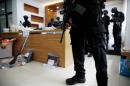 Indonesian anti-terror police from Detachment 88 stand guard near explosive materials and other evidence confiscated in raids on suspected militants, in Jakarta