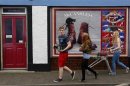 Youths walk past a shop, which has been covered with artwork to make it look more appealing, in the village of Bushmills on the Causeway Coast