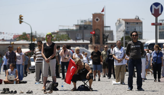 A woman holding a Turkish national flag, sits and rests as people gather for a silent protest at Taksim Square in, Istanbul, Turkey, Thursday, June 20, 2013. After weeks of sometimes violent confrontation with police, Turkish protesters have found a new form of resistance: standing still and silent. (AP Photo/Petr David Josek)