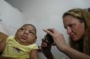 Pediatrician Alexia Harrist from the United States' Centers for Disease Control and Prevention (CDC) takes a picture of 3-month-old Shayde Henrique who was born with microcephaly, after examining him in Joao Pessoa, Brazil, Tuesday, Feb. 23, 2016. U.S. and Brazilian health workers knocked on doors in the poorest neighborhoods of one of Brazil's poorest states Tuesday in a bid to enroll mothers in a study aimed at determining whether the Zika virus is really causing a surge in birth defects. The teams started in Joao Pessoa, the capital of Paraiba state which is one of the epicenters of Brazil's tandem Zika and microcephaly outbreaks. (AP Photo/Andre Penner)