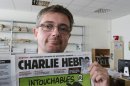 Publishing director of the satyric weekly Charlie Hebdo, Charb, displays the front page of the newspaper as he poses for photographers in Paris, Wednesday, Sept. 19, 2012. Police took up positions outside the Paris offices of the satirical French weekly that published crude caricatures of the Prophet Muhammad on Wednesday that ridicule the film and the furor surrounding it. The provocative weekly, Charlie Hebdo, was firebombed last year after it released a special edition that portrayed the Prophet Muhammad as a 