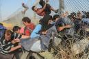 Syrians fleeing the war pass through broken down border fences to enter Turkish territory illegally, near the Turkish Akcakale border crossing in the southeastern Sanliurfa province, on June 14, 2015