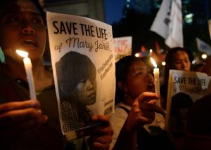 Activists holding candles and portraits of Filipina &hellip;