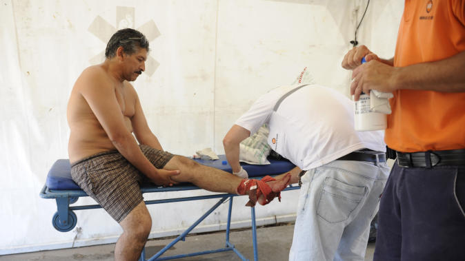 A man is treated after he was bit by a palometa, a type of piranha, while wading in the Parana River in Rosario, Argentina, Wednesday, Dec. 25, 2013. Lifeguards director Federico Cornier said Thursday that thousands of bathers were cooling off from 100 degree temperatures in the Parana River on Wednesday when bathers suddenly came to them complaining of bite marks on their hands and feet. He blamed the attack on palometas, ”a type of piranha, big, voracious and with sharp teeth that can really bite.” (AP Photo/La Capital, Silvina Salinas)