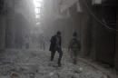 People walk on rubble at a damaged site after what activists said was an air raid by forces loyal to Syrian President Bashar Al-Assad, in Aleppo's al-Saliheen district