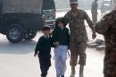 A soldier escorts schoolchildren from the Army Public School that is under attack by Taliban gunmen in Peshawar