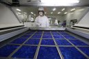 An employee dries newly made solar panels at a factory of a photovoltaic company in Jiaxing
