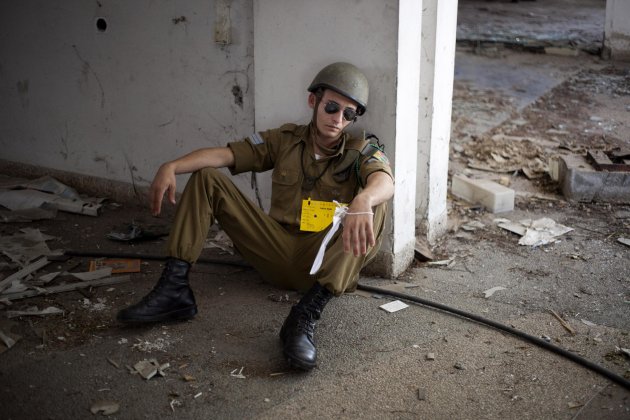 An Israeli soldier acting as if he is wounded waits for Israeli soldiers of the Home Front Command rescue unit during a drill in Azur, near Tel Aviv, Israel, Tuesday, May 28, 2013. Israel has launched a national civil defense drill, which the army said this year will focus on the threat of unconventional weapons at a time of growing regional tensions. (AP Photo/Ariel Schalit)