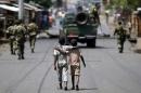 Boys walk behind patrolling soldiers in Bujumbura