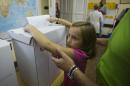 A girl assists her parents to cast a ballot at a polling station in Zagreb, Croatia, Sunday, Sept. 11, 2016. Croatian citizens have started casting ballots in an early parliamentary election that is unlikely to produce a clear winner and could pave the way for more political uncertainty in the European Union's newest member state. (AP Photo/Darko Bandic)