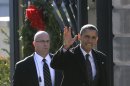 President Barack Obama, accompanied by a U.S. Secret Service agent, waves at reporters shouting questions at him regarding the fiscal cliff as he walks from the White House across Pennsylvania Avenue to Blair House in Washington, Thursday, Dec. 13, 2012, to attend a holiday party for the National Security Council. (AP Photo/Charles Dharapak)
