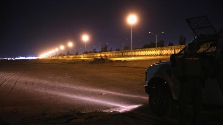 US Border Patrol agents shine headlights along the border fence with Mexico while searching for footprints on November 15, 2013 in Calexico, California