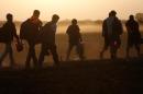 Migrants walk on a dirt road as they approach the Croatian border near the town of Sid