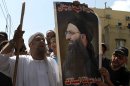 Lebanese protesters hold a poster of hard-line Sunni cleric Sheik Ahmad al-Assir with the Arabic reading, "There are men in Sidon. Anytime you call us we will respond," and chant slogans against Hezbollah after the Friday prayer in the southern port city of Sidon, Lebanon, Friday, June 28, 2013. Lebanese troops have fired in the air to disperse dozens of Sunni Muslims demonstrating in support of a hard-line cleric who has been on the run since the military crushed his fighters earlier this week. (AP Photo/Mohammed Zaatari)
