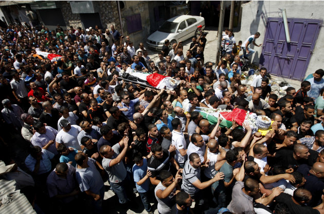 Palestinos transportan en el campamento de refugiados de Qalandia los féretros de tres palestinos muertos por soldados israelíes en Cisjordania, el 26 de agosto del 2013 (AP Foto/Majdi Mohammed)
