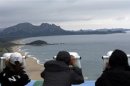 South Koreans look at the North Korean territory through binoculars at an observation post, just south of the demilitarised zone separating the two Koreas, in Goseong