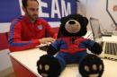 Spidey Bear sits on a table in front of U.S. Soccer's Neil Buethe at the Sao Paulo Futebol Clube, Brazil, Saturday June 28, 2014. Spidey Bear turned from his perch toward the television and sat intently and quietly (as usual) on a table some 8 feet from the big screen as Brazil took penalty kicks and salvaged its World Cup with a thrilling 3-2 win over Chile. It has been quite an adventure tour this summer for the stuffed black bear from Iowa City belonging to the nephews of Buethe, 6-year-old Graeme Thomas and little brother Miles, 3. (AP Photo/Julio Cortez)