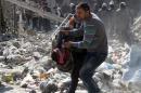 A Syrian man carries the body of a victim out of the rubble of a destroyed building after an alleged air strike by pro-regime forces on the northern city of Aleppo, on February 3, 2014