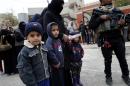 Children look on as a soldier from the Iraqi special forces stands guard during food distribution in eastern Mosul