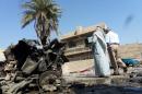 Iraqis look at the remains of a vehicle following an explosion on October 27, 2013, in the the Mashtal district of the capital Baghdad