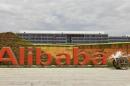 A worker walks past a logo of Alibaba Group at its headquarters on the outskirts of Hangzhou