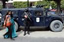Tunisians walk past police during a demonstration in Tunis on March 20, 2015, two days after gunmen attacked the National Bardo Museum