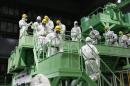 Members of the media and TEPCO employees walk down the steps of a fuel handling machine inside the No.4 reactor building in Fukushima