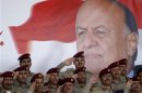 Military officers salute in front of poster of Yemen's President Abd-Rabbu Mansour Hadi during a military parade celebrating the 50th anniversary of North Yemen's revolution in Sanaa