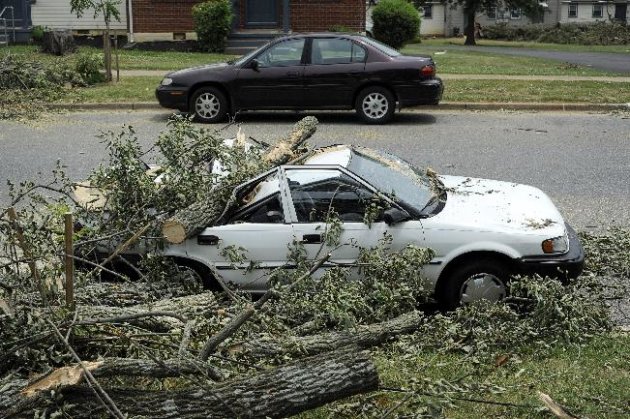 A car sits, crushed by a fallen tree, on Carrington Road in Lynchburg, Va., July 1, 2012. Two days after storms tore across the eastern U.S., power outages were forcing people to get creative to stay cool in dangerously hot weather. Temperatures approached 100 degrees in many storm-stricken areas, and utility officials said the power will likely be out for several more days. (AP Photo/The News & Advance, Parker Michels-Boyce)