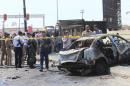 Iraqi security forces with people gather at the site of a car bomb attack in Basra