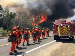 Fire crews walk on U.S. Highway 20 as a fire approaches &hellip;