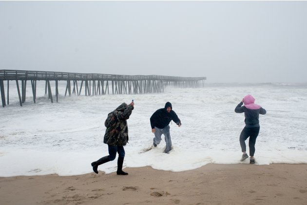 Beachgoers along the oceanfront get soaked by an incoming wave as Hurricane Sandy begins to arrive in Virginia Beach, Virginia.