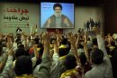Hezbollah supporters raise their hands in salute as Hezbollah leader Sheik Hassan Nasrallah speaks on a screen via a video link from a secret place, during a rally to mark the "wounded resistants day," in the southern suburb of Beirut, Lebanon, Friday, June 14, 2013. Nasrallah said his group will continue to fight in Syria 