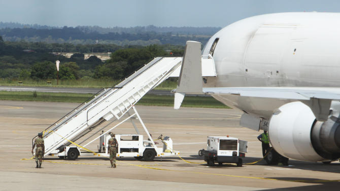 Zimbabwean Armed Soldiers patrol around a United States registered cargo plane at Harare International Airport in Harare, Zimbabwe, Monday, Feb,15.2016. Zimbabwean aviation authorities impounded a U.S.-registered cargo jet after a dead body later believed to be a stowaway and millions of South African rand were found on board, a senior official said Monday. (AP Photo/Tsvangirayi Mukwazhi)