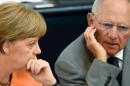 German Finance Minister Wolfgang Schaeuble (R) and Chancellor Angela Merkel chat during a session on the Greek crisis at the Bundestag in Berlin