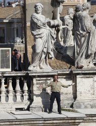 An unidentified man, bottom right, holds a copy of the Holy Bible as he stands on the edge of the colonnade that surrounds St. Peter's square at the Vatican, during a beatification mass celebrated by Pope Benedict XVI, Sunday, Oct. 23, 2011. Vatican gendarmes, a bishop and the pope's own bodyguard eventually talked the man down from the upper reaches of the colonnade after he shouted, "Pope, where is Christ?" in English. The disruption came toward the end of a two-hour Mass Sunday to canonize three 19th-century founders of religious orders: Italian bishop and missionary Monsignor Guido Maria Conforti, Spanish nun Sister Bonifacia Rodriguez de Castro and an Italian priest who worked with the poor, the Rev. Luigi Guanella. (AP Photo/Pier Paolo Cito)