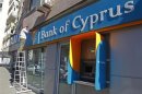 A worker paints a wall above a branch of Bank of Cyprus in Bucharest