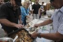 Polychronopoulos, from the group called "O Allos Anthropos", or "The Fellow Man", distributes food portions at a soup kitchen in Athens