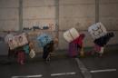 Women porters carry bundles on their backs for transport across the El Tarajal boarder separating Morocco and Spain's North African enclave of Ceuta, in Ceuta on December 4, 2014