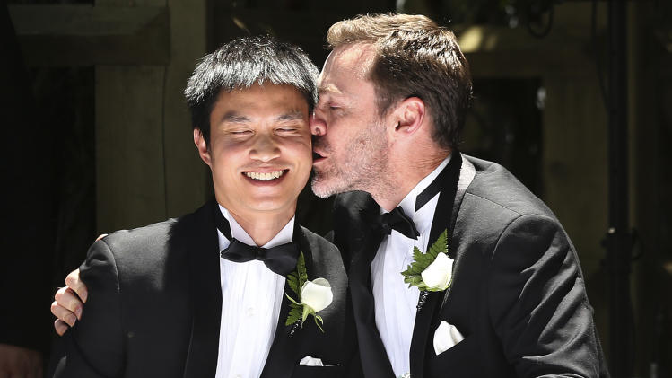 Ivan Hinton, right, gives his partner Chris Teoh a kiss after taking their wedding vows during a ceremony at Old Parliament House in Canberra, Australia, Saturday, Dec. 7, 2013. Dozens of same-sex couples from all around the country are taking advantage of the Australia Capital Territory's new law allowing same-sex marriages. But the unions may be short lived if the High Court on Dec. 12, 2013 rules in favor of a Commonwealth government challenge to overrule the states law. (AP Photo/Rob Griffith)