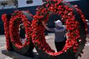 Visitors pay their respects to Australia's Anzac soldiers as they visit a Wall of Remembrance covered with poppies, in front of the Queen Elizabeth cruise ship in Sydney on March 3, 2015