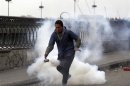 A protester opposing Egyptian President Mohamed Mursi flees from tear gas fired by riot police during clashes along Qasr Al Nil bridge leading to Tahrir Square in Cairo