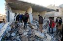 People inspect a site hit by what residents said were airstrikes carried out by the Russian air force in the town of Turmanin
