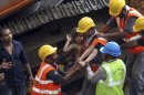 Rescue workers carry a girl out from the rubble of a building that collapsed in Mumbai, India, Friday, Sept. 27, 2013. The apartment building collapsed in India's financial capital of Mumbai early Friday, killing people and sending rescuers racing to reach dozens of people trapped in the rubble. (AP Photo/Rajanish Kakade)